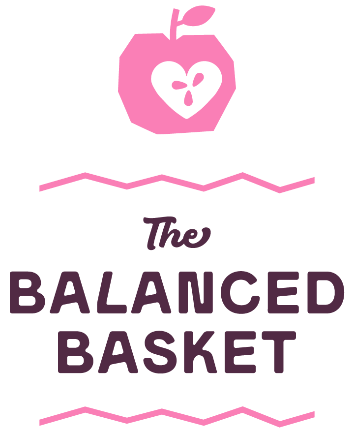 Logo With A Pink Apple Featuring A Heart-Shaped Core Above The Words &Quot;The Balanced Basket&Quot; In Bold, Dark Lettering, Separated By Wavy Pink Lines.